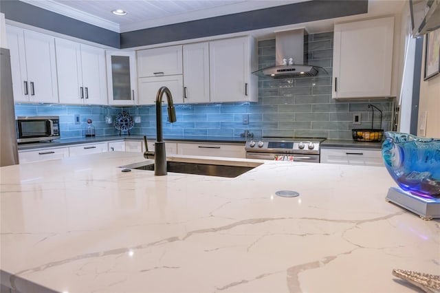 kitchen featuring wall chimney exhaust hood, sink, white cabinetry, stainless steel appliances, and decorative backsplash