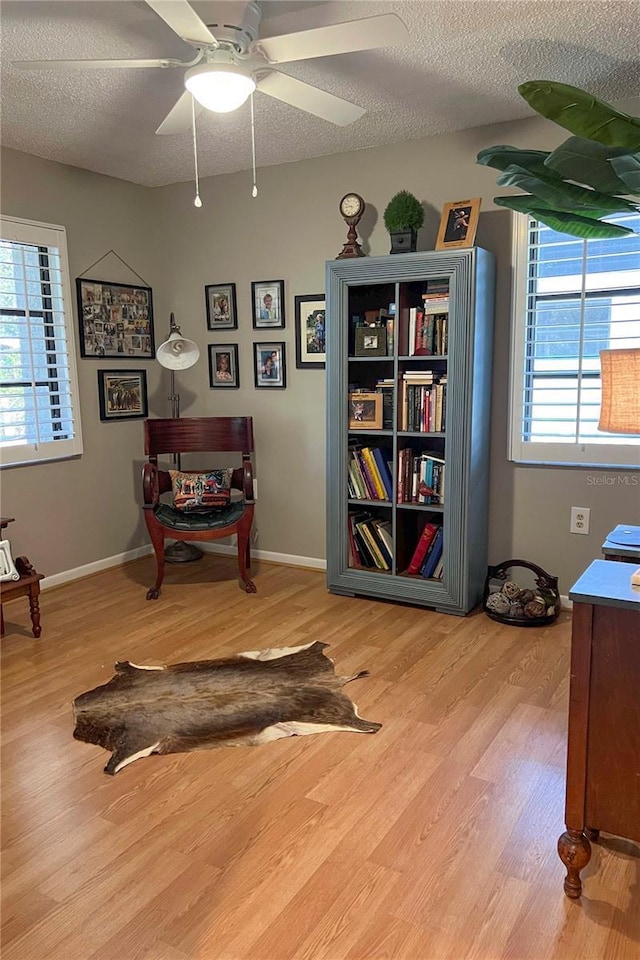 sitting room featuring ceiling fan, wood-type flooring, and a textured ceiling