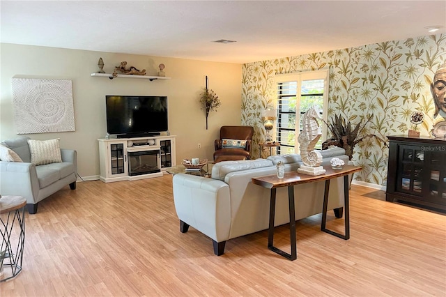 living room with a stone fireplace and light wood-type flooring