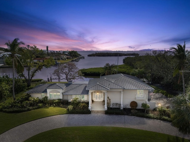 view of front of property with a lawn and a water view