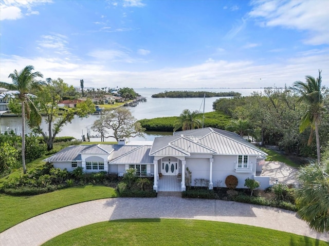 view of front of house with metal roof, a front lawn, a standing seam roof, and a water view