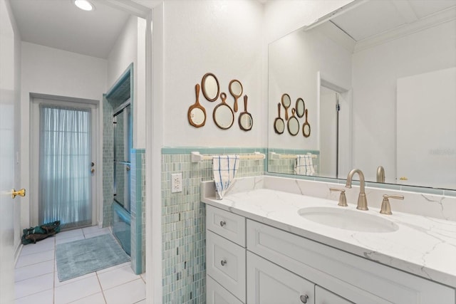 7056 Hawks Harbor Cir, Bradenton, FL 34207 - bathroom featuring tile patterned floors, combined bath / shower with glass door, tile walls, wainscoting, and vanity