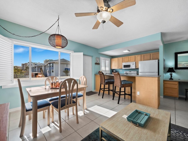 tiled dining room with a textured ceiling and ceiling fan