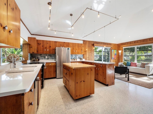 kitchen featuring stainless steel refrigerator, sink, backsplash, wooden counters, and a center island