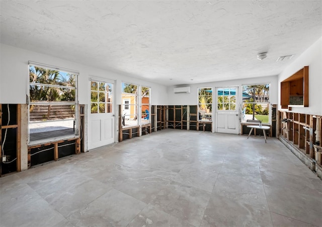 unfurnished living room featuring a healthy amount of sunlight and a wall mounted AC