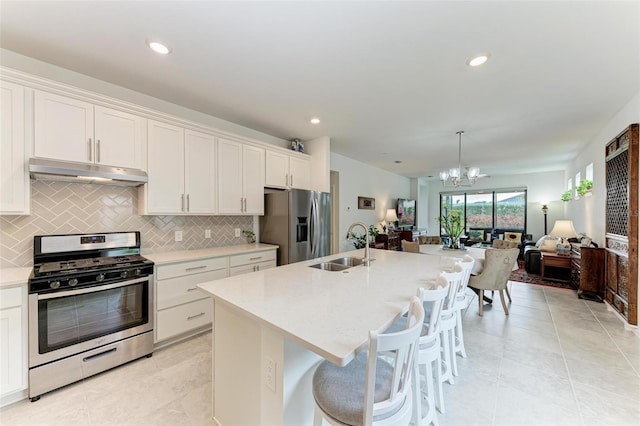 kitchen with an island with sink, appliances with stainless steel finishes, a kitchen breakfast bar, white cabinets, and sink