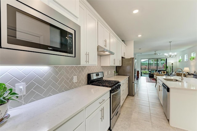 kitchen featuring backsplash, sink, hanging light fixtures, stainless steel appliances, and white cabinets