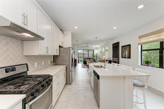 kitchen with white cabinets, sink, appliances with stainless steel finishes, and an island with sink