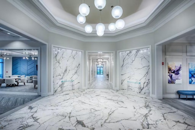 interior space with an inviting chandelier, ornamental molding, and a raised ceiling