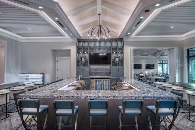 kitchen featuring a notable chandelier, pendant lighting, a kitchen bar, crown molding, and high vaulted ceiling