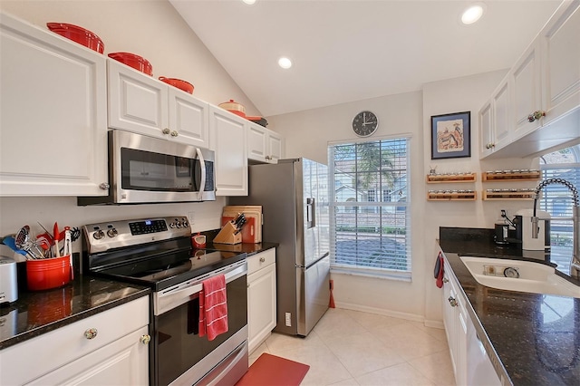 kitchen with lofted ceiling, white cabinets, sink, stainless steel appliances, and light tile patterned flooring