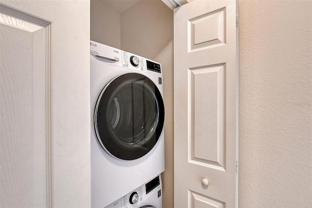 clothes washing area featuring stacked washing maching and dryer