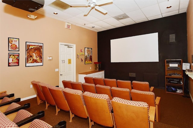 home theater room with ceiling fan, carpet flooring, and a drop ceiling