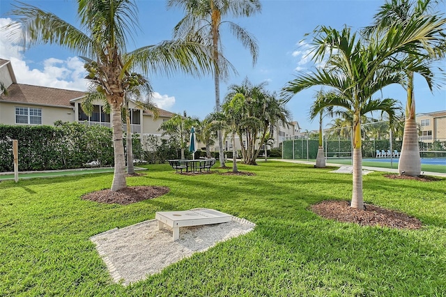 view of community featuring tennis court and a yard