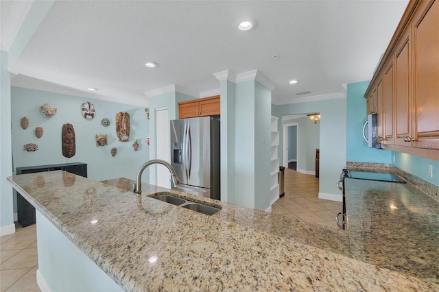 kitchen with appliances with stainless steel finishes, sink, kitchen peninsula, light stone counters, and light tile patterned floors