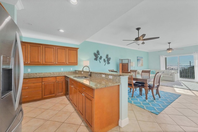 kitchen with light stone countertops, stainless steel appliances, kitchen peninsula, and sink