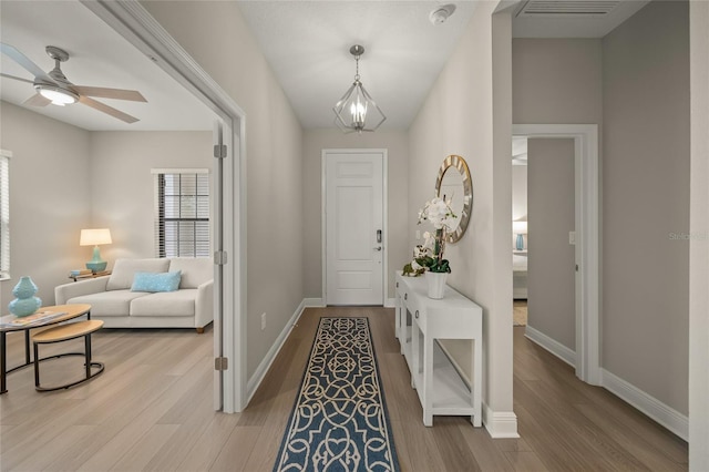 foyer featuring ceiling fan with notable chandelier and light hardwood / wood-style flooring