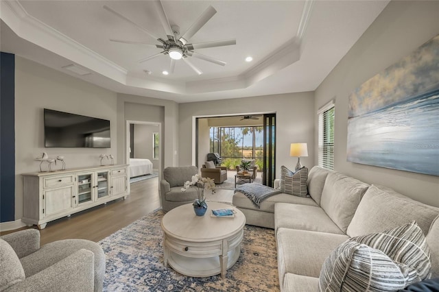 living room featuring a raised ceiling, ceiling fan, crown molding, and hardwood / wood-style floors