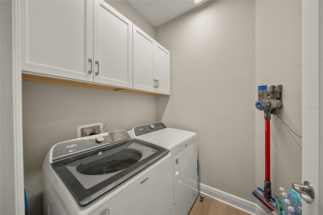 laundry area featuring light wood-type flooring, washer and dryer, and cabinets