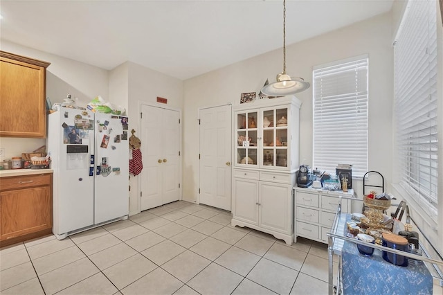 kitchen with decorative light fixtures, white fridge with ice dispenser, and light tile patterned flooring