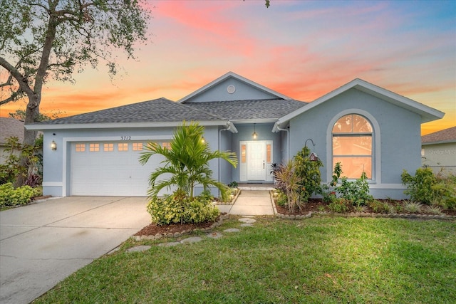 view of front of home with a garage and a lawn