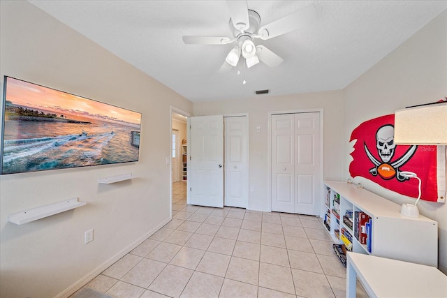 interior space with ceiling fan, light tile patterned flooring, and multiple closets