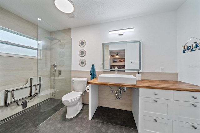 bathroom with sink, toilet, a textured ceiling, and an enclosed shower