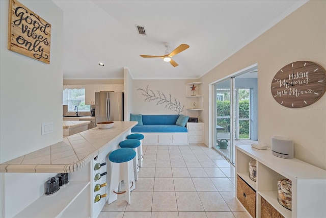 tiled living room with sink, ceiling fan, and ornamental molding