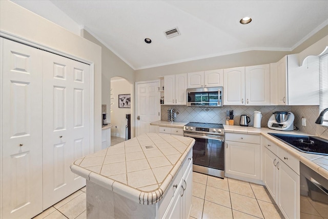 kitchen featuring sink, a center island, decorative backsplash, lofted ceiling, and stainless steel appliances