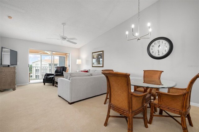 dining room featuring vaulted ceiling, light colored carpet, and ceiling fan with notable chandelier