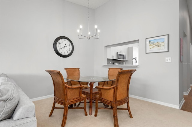 carpeted dining room featuring a chandelier, a high ceiling, and sink