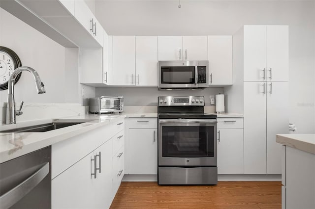 kitchen with stainless steel appliances, white cabinets, and sink