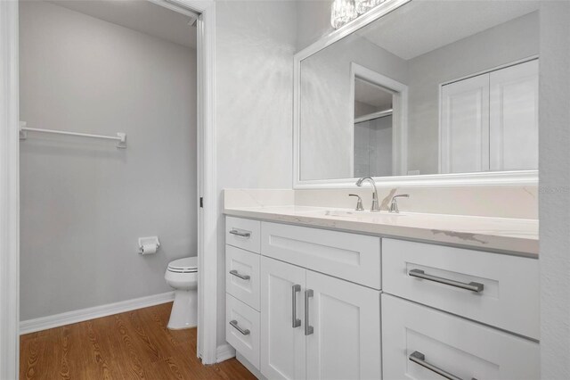 bathroom featuring toilet, vanity, and hardwood / wood-style flooring