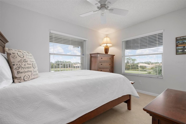 bedroom featuring ceiling fan, a textured ceiling, and carpet floors