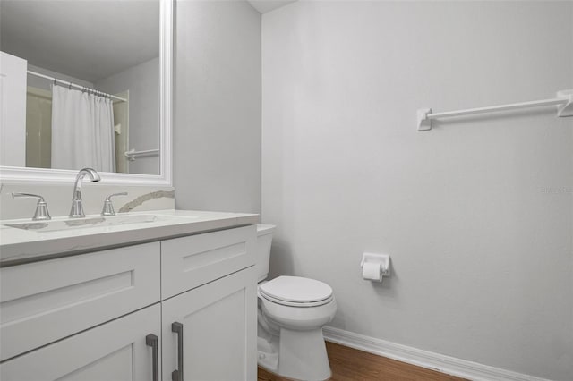 bathroom with toilet, hardwood / wood-style flooring, vanity, and curtained shower