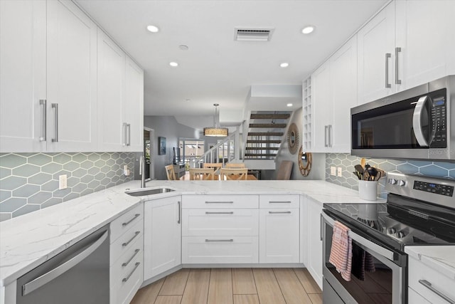 kitchen with white cabinets, appliances with stainless steel finishes, and pendant lighting