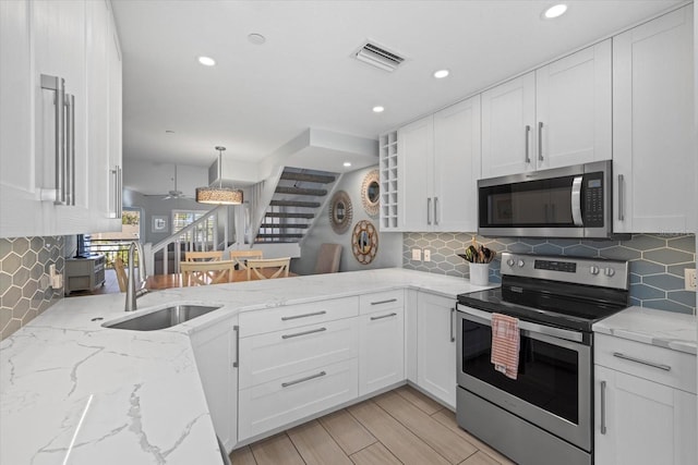 kitchen with sink, stainless steel appliances, white cabinetry, and hanging light fixtures