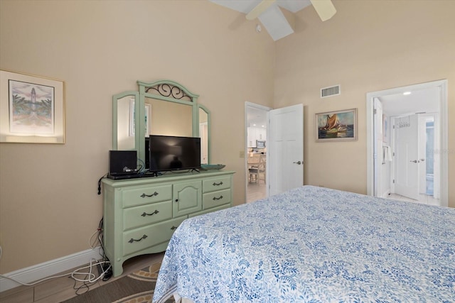 bedroom featuring ceiling fan, high vaulted ceiling, and ensuite bath