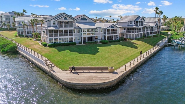 back of house featuring a water view and a lawn