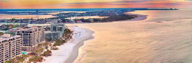 aerial view at dusk with a beach view and a water view