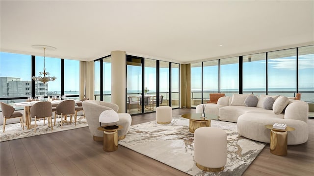 living room with a wall of windows, a water view, hardwood / wood-style floors, and a notable chandelier