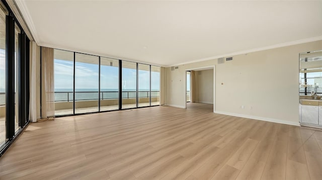 empty room featuring light hardwood / wood-style flooring, crown molding, and a water view