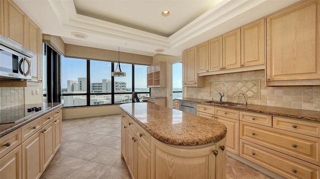 kitchen featuring decorative light fixtures, a center island, a raised ceiling, sink, and appliances with stainless steel finishes