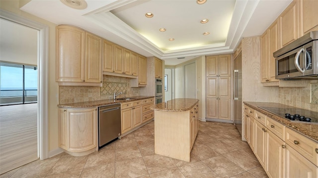 kitchen featuring light brown cabinets, a kitchen island, stainless steel appliances, and a raised ceiling