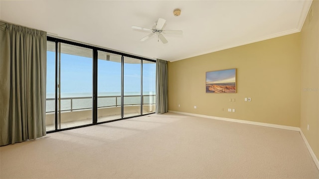 empty room featuring light carpet, ceiling fan, a wealth of natural light, and a water view