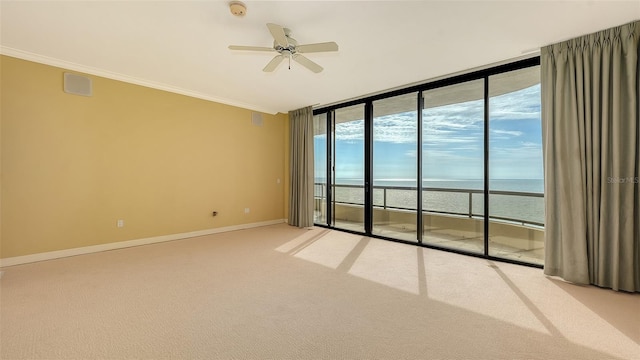 carpeted spare room with ceiling fan, crown molding, and a water view