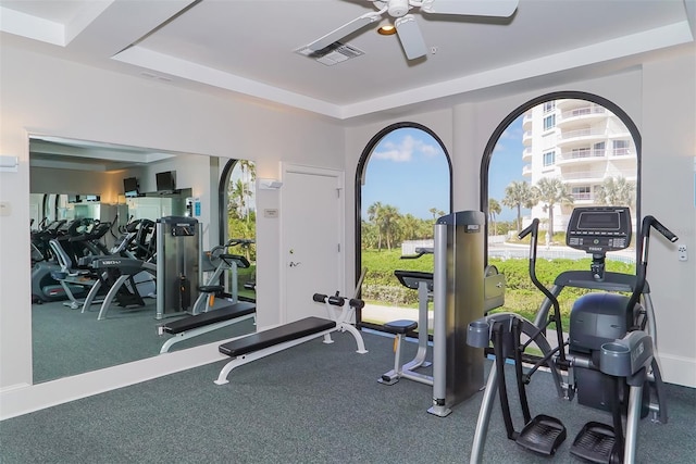 workout area with ceiling fan and a raised ceiling