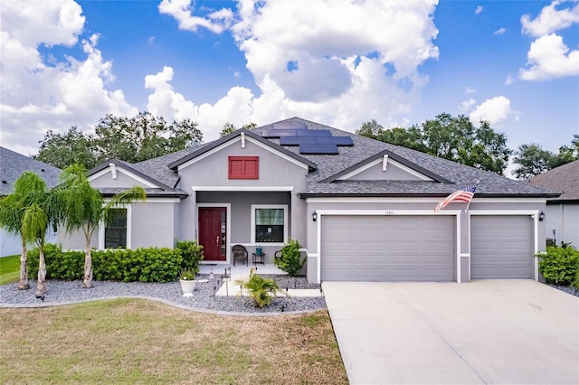 view of front of property with a front lawn, a garage, and solar panels