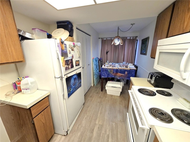 kitchen with white appliances, pendant lighting, and light wood-type flooring