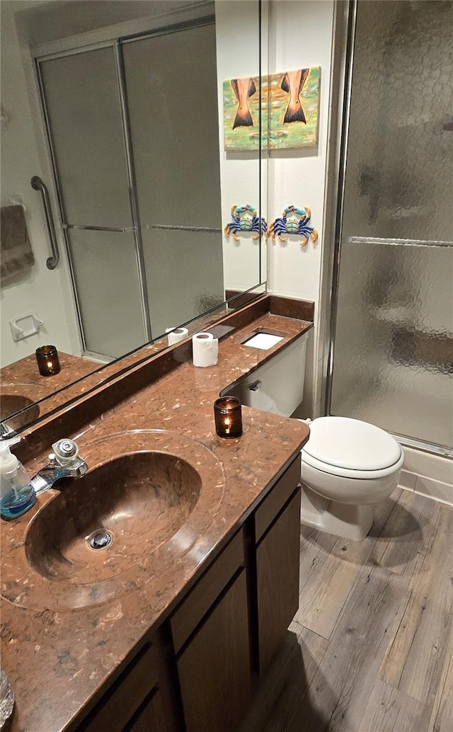 bathroom featuring hardwood / wood-style floors, toilet, a shower with door, and vanity